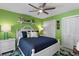 Bright bedroom featuring a white wood frame bed, ceiling fan, and vivid green walls at 13810 Lake Village Pl, Tampa, FL 33618