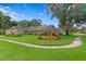 Charming single-story home with a well-manicured front lawn and colorful landscaping, stone accents, and mature trees at 13810 Lake Village Pl, Tampa, FL 33618