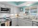 Bright kitchen with white cabinets, granite counters, stainless appliances and view to outside at 13810 Lake Village Pl, Tampa, FL 33618