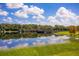 Scenic pond reflecting the blue sky and clouds, surrounded by green grass and trees, promoting a peaceful environment at 13810 Lake Village Pl, Tampa, FL 33618