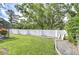 A beautiful backyard with manicured lawn, mature trees, and a stylish textured privacy wall at 13903 Wolcott Dr, Tampa, FL 33624