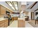 A well-lit kitchen with wood cabinets, stainless steel appliances, a breakfast bar and a view of the adjacent living spaces at 13903 Wolcott Dr, Tampa, FL 33624