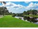 Community pond with lush green lawn on a bright sunny day, providing tranquil water views for residents at 16137 Churchview Dr, Lithia, FL 33547