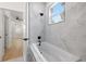 Bathroom featuring a soaking tub with marble look tile surround, window, and black fixtures at 1625 39Th S St, St Petersburg, FL 33711