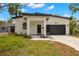 Modern single-Gathering home featuring a sleek black garage door, white facade, and minimalist landscaping at 1625 39Th S St, St Petersburg, FL 33711