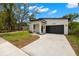 Modern home exterior with a black garage door, a well-manicured lawn and a concrete driveway at 1625 39Th S St, St Petersburg, FL 33711
