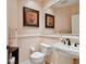 Powder room featuring a pedestal sink, toilet, and framed floral art, enhancing the home's elegant feel at 17923 Arbor Haven Dr, Tampa, FL 33647
