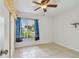 Bedroom with tiled floors, ceiling fan, and window with blue curtains at 1944 Hastings Ln, Clearwater, FL 33763