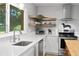 Close up of the modern kitchen featuring white cabinets, stainless steel appliances and floating wood shelves at 2136 Cunningham Dr, Clearwater, FL 33763