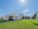 Large backyard with patio, lawn, and view of neighboring houses under a blue sky at 33488 Elm Hill Br, Wesley Chapel, FL 33545
