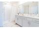 Bright bathroom features dual sinks, white cabinets, and a shower with a white curtain at 33488 Elm Hill Br, Wesley Chapel, FL 33545