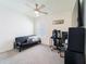 Bright bedroom with a modern ceiling fan, a dark futon, and a desk with dual monitors at 33488 Elm Hill Br, Wesley Chapel, FL 33545