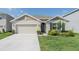 Charming single-story home showcasing a manicured lawn, blooming shrubs, and a two-car garage at 33488 Elm Hill Br, Wesley Chapel, FL 33545