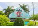 Charming Sunset Palms community entrance sign with lush landscaping and swaying palm trees at 34041 Azalea N Dr, Pinellas Park, FL 33781