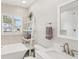 Bright bathroom with freestanding tub, mosaic tile accent wall, and convenient floating shelves at 3966 High Bluff Dr, Largo, FL 33770