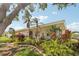 Charming single-story home with vibrant landscaping, including mature palms, shrubs, and flowering plants at 3966 High Bluff Dr, Largo, FL 33770