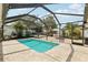 Screened-in pool area showcasing a pool, beautiful stone patio, lush tropical plants, and an outdoor seating area at 3966 High Bluff Dr, Largo, FL 33770