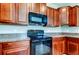 This kitchen features black appliances, granite countertops, wood cabinets, and an overhead microwave at 4023 Wild Senna Blvd, Tampa, FL 33619