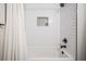 White bathtub and shower features a subway tile surround and a decorative mosaic niche for storage at 4205 N Suwanee Ave, Tampa, FL 33603