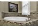 Close-up of a sleek, standalone bathtub with decorative tile surround and natural light from a window at 4239 Woodland Retreat Blvd, New Port Richey, FL 34655
