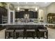 Gourmet kitchen featuring a center island with seating, dark cabinetry, stone backsplash and stainless steel appliances at 4239 Woodland Retreat Blvd, New Port Richey, FL 34655