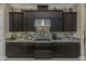 Gourmet kitchen boasts dark cabinetry, stone countertops, stainless steel appliances, and stylish backsplash at 4239 Woodland Retreat Blvd, New Port Richey, FL 34655