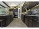 Modern kitchen featuring dark wood cabinets, stainless steel appliances, granite countertops and tile floors at 4239 Woodland Retreat Blvd, New Port Richey, FL 34655