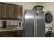 Functional laundry room with cabinets, granite counters, stainless steel refrigerator and full size washer and dryer at 4239 Woodland Retreat Blvd, New Port Richey, FL 34655