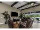 Spacious living room with beamed ceiling, large windows, and comfortable leather seating is perfect for entertaining at 4239 Woodland Retreat Blvd, New Port Richey, FL 34655