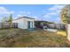 View of the fenced backyard with grass, tiled patio, and screened-in porch at 4309 Cedar Grove St, Holiday, FL 34691