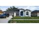 Charming single-story home with an attached garage, arched windows, and a manicured lawn and black car at 6213 Ashfield Pl, Wesley Chapel, FL 33545