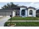 Charming single-story home with an attached garage, arched windows, and well-manicured lawn at 6213 Ashfield Pl, Wesley Chapel, FL 33545