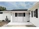 Inviting front porch with a tile floor, white brick walls, and black shutters at 6508 Lenore Dr, Tampa, FL 33634