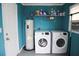 Laundry area with washer, dryer, and water heater against a teal blue wall at 6508 Lenore Dr, Tampa, FL 33634