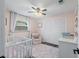 Bright Bedroom featuring a white crib, soft rug, large closet, and comfortable chair, ideal for a growing  at 6521 69Th N Ave, Pinellas Park, FL 33781
