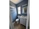 Small, blue bathroom features a vanity, toilet, mirror, and shelves at 6527 S West Shore Cir, Tampa, FL 33616