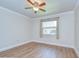 Bedroom features a ceiling fan, window, crown molding, and light-colored wood flooring at 6550 Teak Ct, Zephyrhills, FL 33542