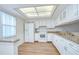 Bright kitchen featuring white cabinets, granite counters, modern appliances, and wood-look flooring at 6550 Teak Ct, Zephyrhills, FL 33542