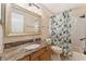 Well-lit bathroom features granite countertops, a framed mirror, and a shower with a floral patterned curtain at 709 Grand Canyon Dr, Valrico, FL 33594