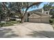 Inviting home with a spacious driveway, three-car garage, and mature landscaping with a lovely tree at 709 Grand Canyon Dr, Valrico, FL 33594
