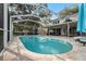 Aerial side view of backyard pool featuring a screened enclosure and brick pool deck, with patio seating at 709 Grand Canyon Dr, Valrico, FL 33594