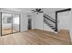Modern living area with natural light, wood floors, stairs, and a view to the kitchen at 7318 Bellows Falls Ln, Hudson, FL 34667