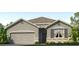 Charming single-story home with a gray exterior, stone accents, a two-car garage, and well-maintained landscaping at 7718 Wheat Stone Dr, Zephyrhills, FL 33540