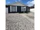 View of single-story home with dark siding, white trim, stone ground cover, and 'For Sale' sign at 9106 Telford Ct, Tampa, FL 33615