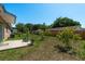Spacious backyard with a concrete patio, lush grass, and a variety of plants and trees at 920 York Dr, Brandon, FL 33510