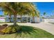 Inviting single-story home featuring lush landscaping, mature palm trees, and an attached single car garage at 9485 Treasure Ne Ln, St Petersburg, FL 33702