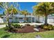 Charming single story home with a well-manicured front yard featuring lush landscaping and mature palm trees at 9485 Treasure Ne Ln, St Petersburg, FL 33702