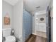 Well-lit bathroom showing toilet, vanity, and blue shower curtain with laundry room visible at 9591 Commodore Dr, Seminole, FL 33776