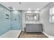 Bright bathroom with a tiled shower, gray vanity with double sinks, and wood-look tile floor at 9591 Commodore Dr, Seminole, FL 33776