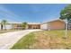 Single story home featuring a spacious driveway, two-car garage, and tropical landscaping at 9591 Commodore Dr, Seminole, FL 33776